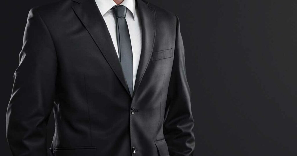 Closeup of man wearing a suit of high quality material and slim grey tie