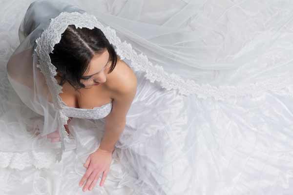 Aerial view of bride sitting on the floor with her dress draped around her.