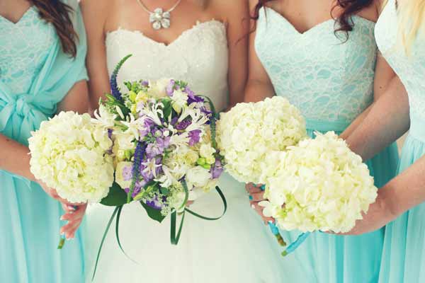 Three bridesmaids with bride holding bouquet of flowers in a bundle.