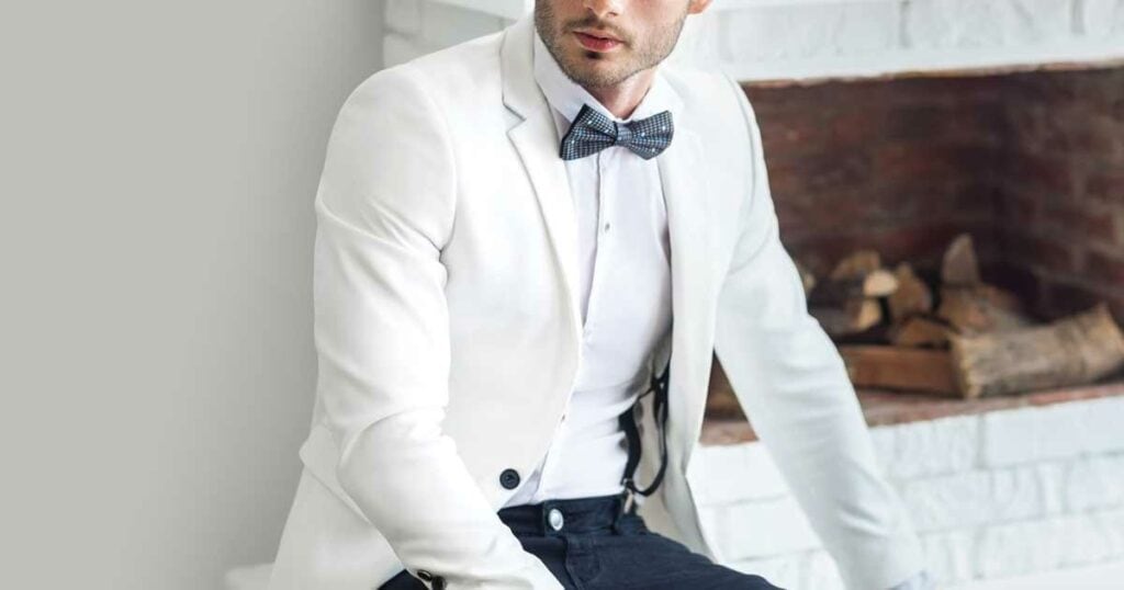 Man in white fitted tux with blue pants and blue bow tie.