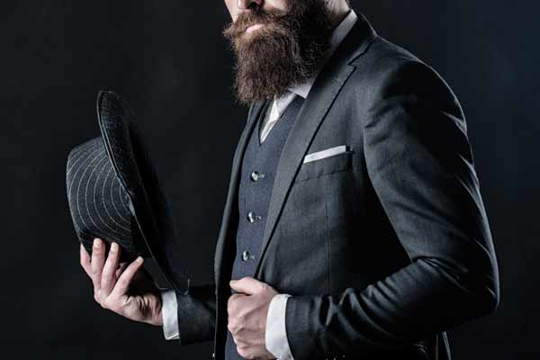Man with beard in fancy suit with vest and hat.