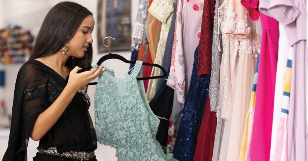 Woman looking at fancy dresses at Fashion Dreams Inc.