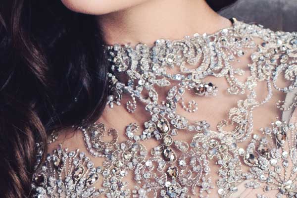 Closeup of the neckline and upper chest of a woman wearing a gorgeous hand-sewn beaded and crystal dress.