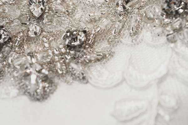 Closeup of a hand-beaded appliqué with clear and silver stones, on a wedding dress