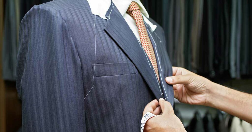 Tailor's hands altering a man's rental suit.